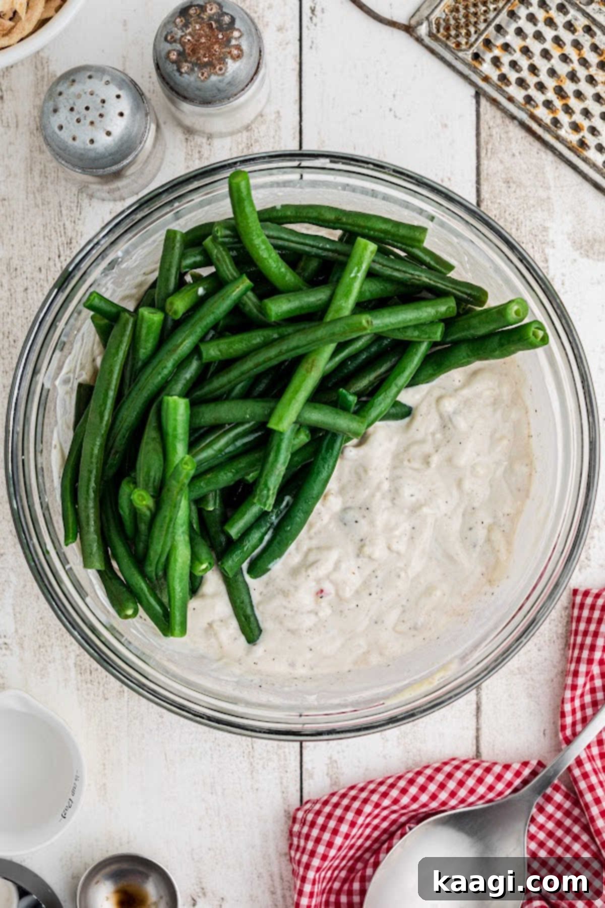 A mixing bowl with green beans and a delicious sauce waiting to be mixed.
