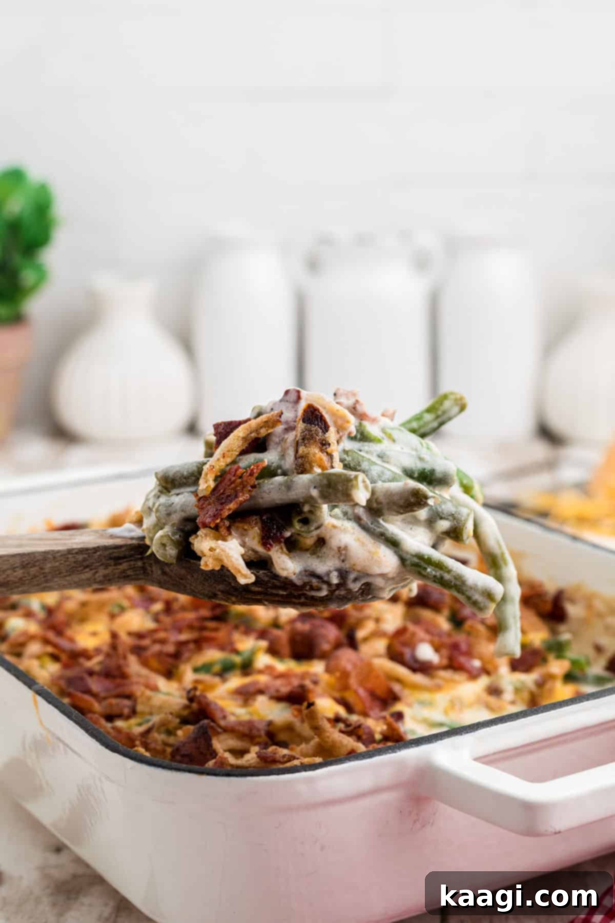 A spoon full of loaded green bean casserole being lifted out of the casserole dish.