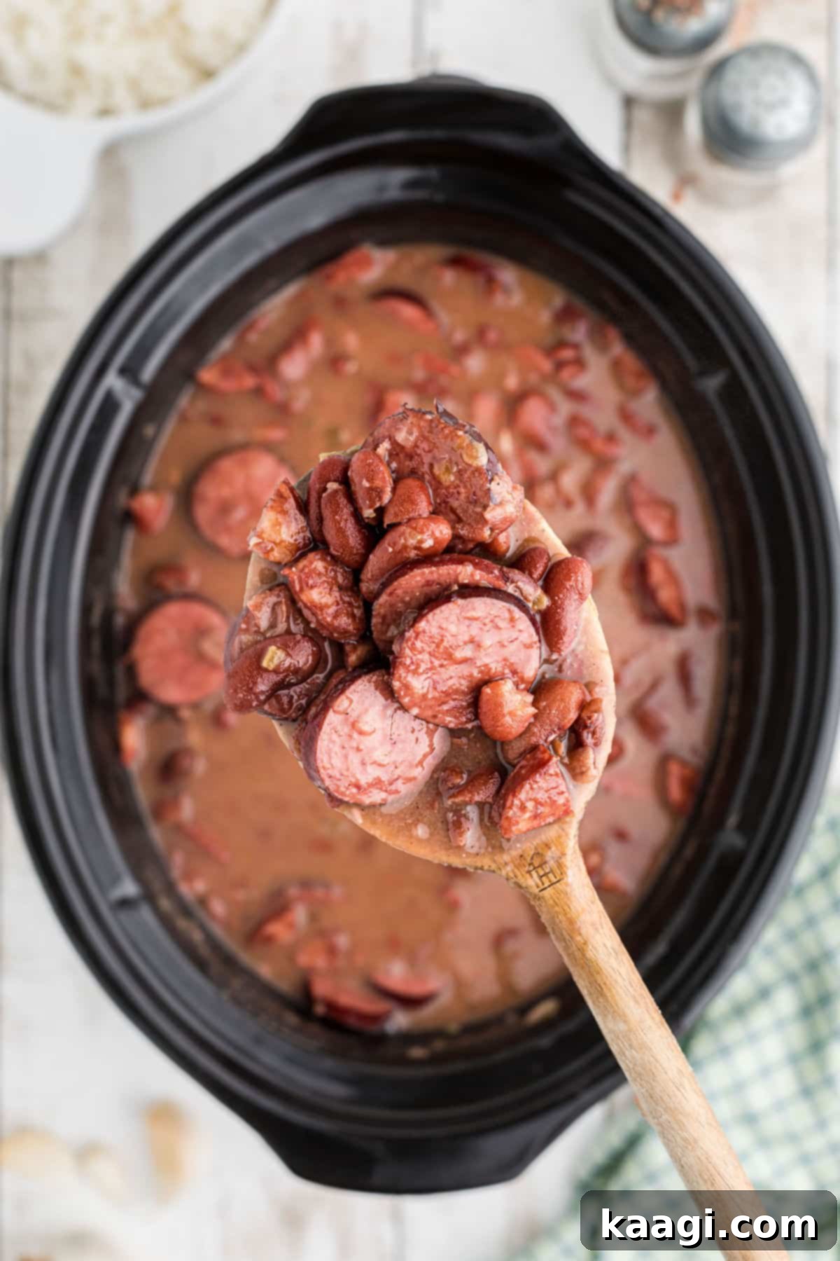 Soulful Slow Cooker Cajun Red Beans and Rice 8 A spoon lifting some red beans out of a slow cooker.