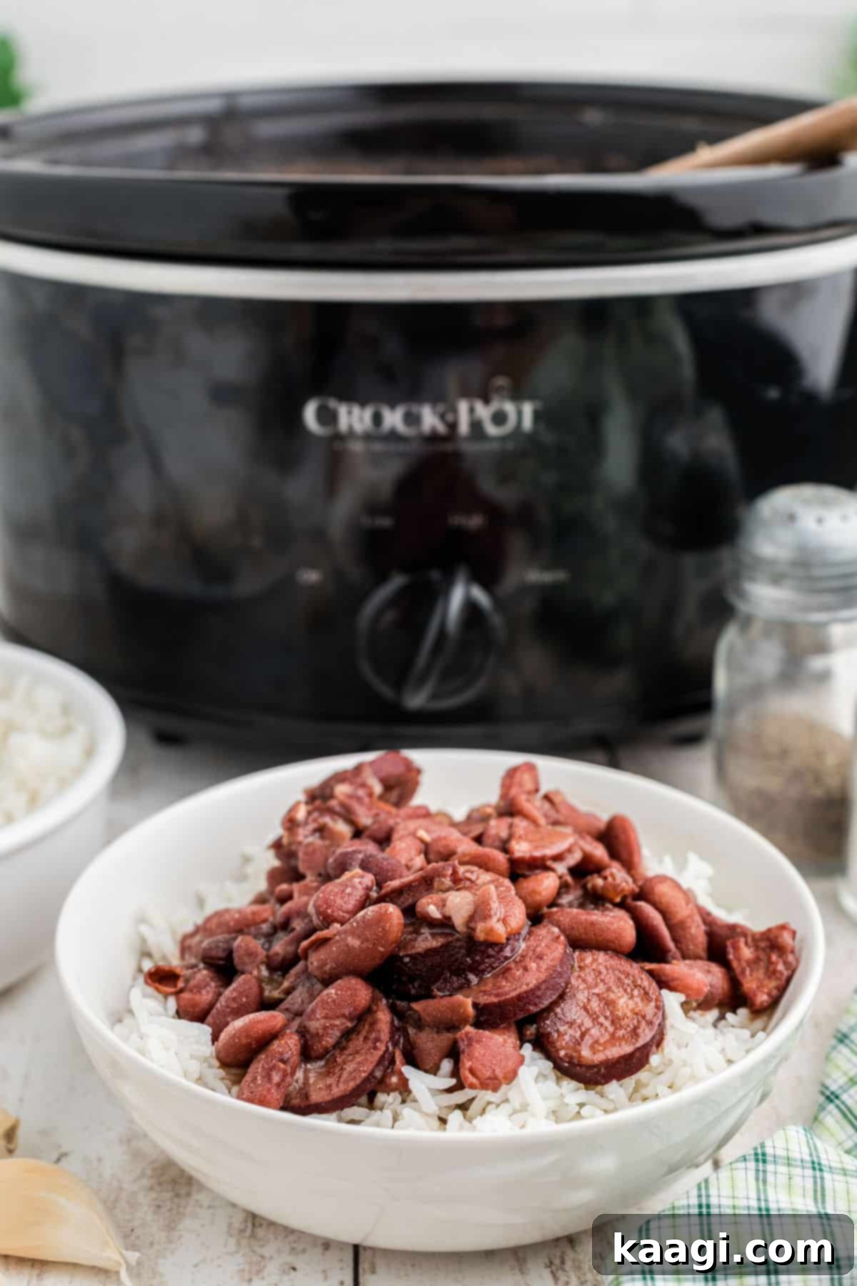 Soulful Slow Cooker Cajun Red Beans and Rice 6 A bowl of Cajun Red Beans and Rice in front of a slow cooker.