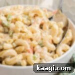 Close up of a bowl of creamy KFC Macaroni Salad with a spoon digging in.