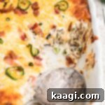 Jalapeno Popper Tater Tot Casserole with a serving spoon still in the dish, showcasing its irresistible texture.