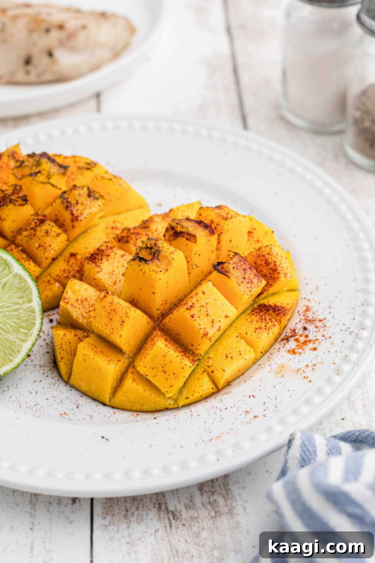 Perfectly grilled mango halves, seasoned with spices and herbs, on a elegant serving plate.