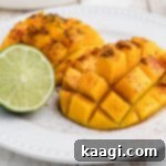 A close up of a plate with two pieces of grilled mango and a lime.