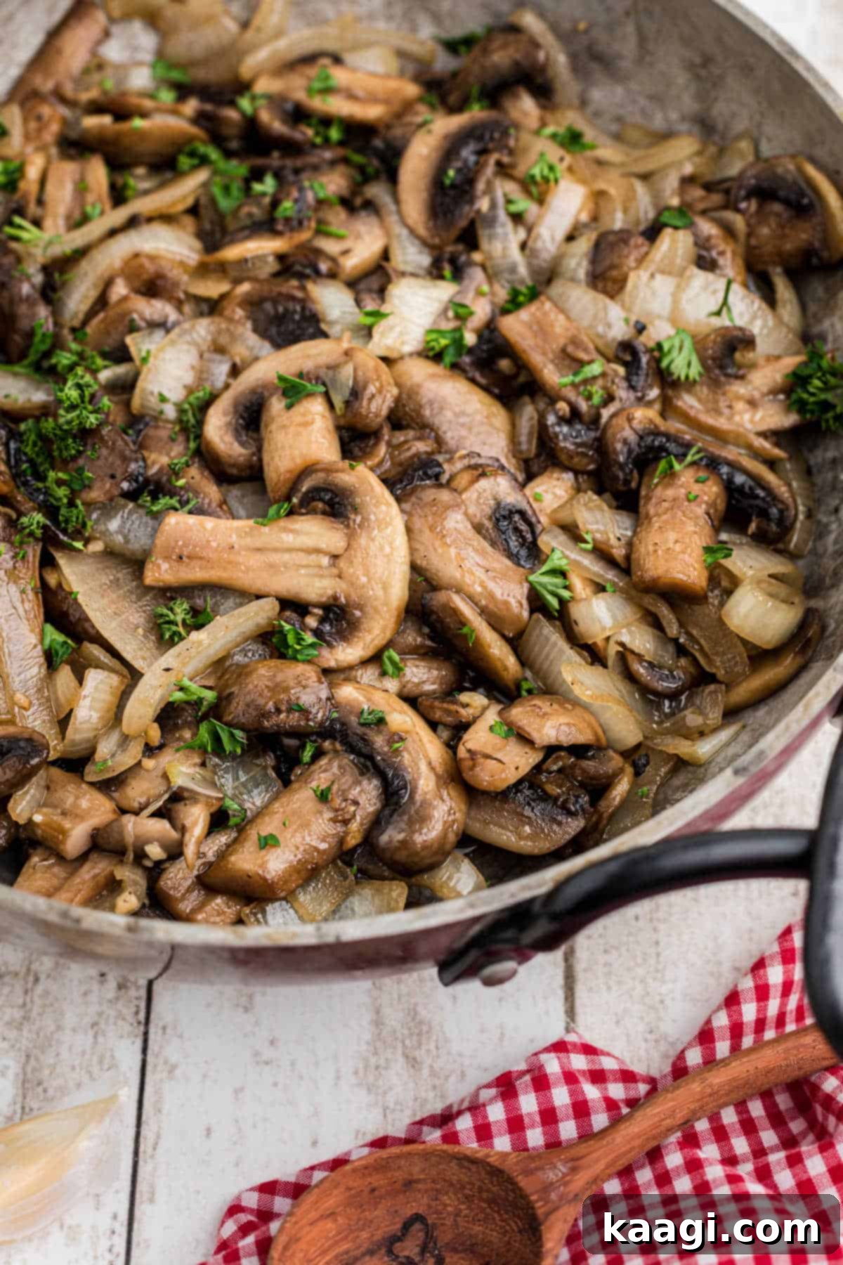 A close-up side view of a skillet filled with golden-brown Texas Roadhouse Sauteed Mushrooms, garnished with fresh parsley.