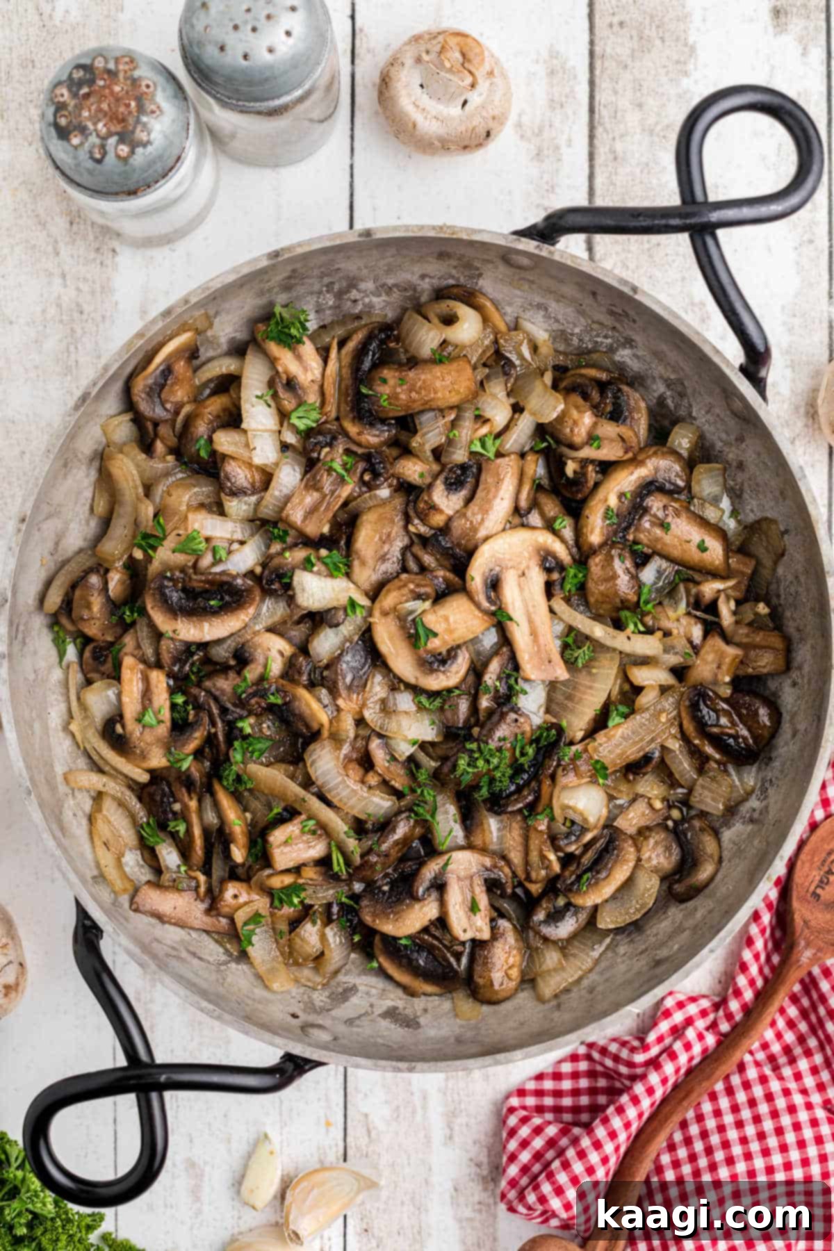 An overhead shot of a robust cast iron skillet generously filled with perfectly cooked, glistening copycat Texas Roadhouse Sauteed Mushrooms.