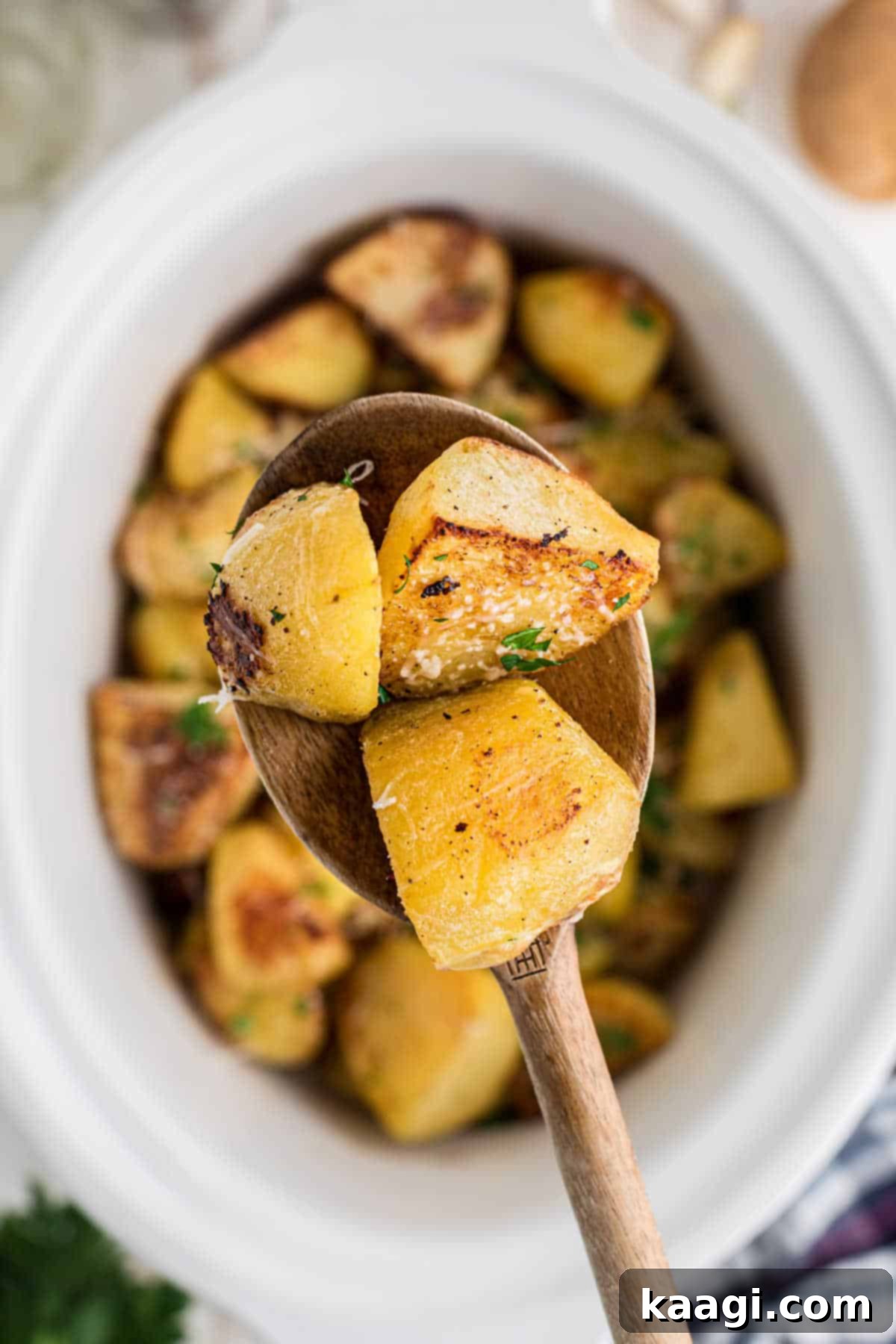 Perfectly Tender Slow Cooker Roast Potatoes 7 A spoon lifting out some slow cooker roast potatoes, showcasing their fluffy interior.