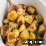 Perfectly Tender Slow Cooker Roast Potatoes 8 Slow cooker roast potatoes recipe with a wooden spoon digging in, showing the perfect texture.