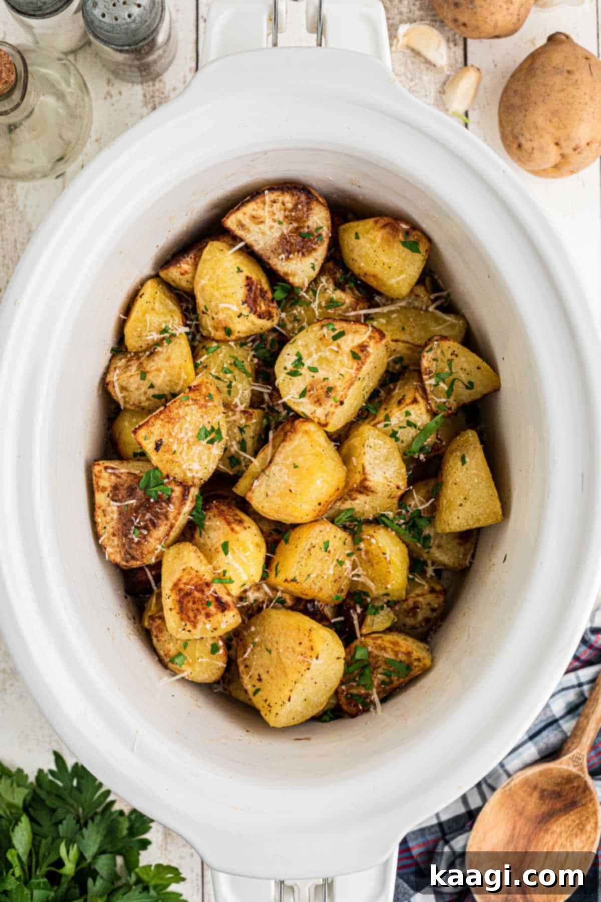 Perfectly Tender Slow Cooker Roast Potatoes 5 Overhead shot of slow cooker roast potatoes, showing the final sprinkles of parmesan and parsley.