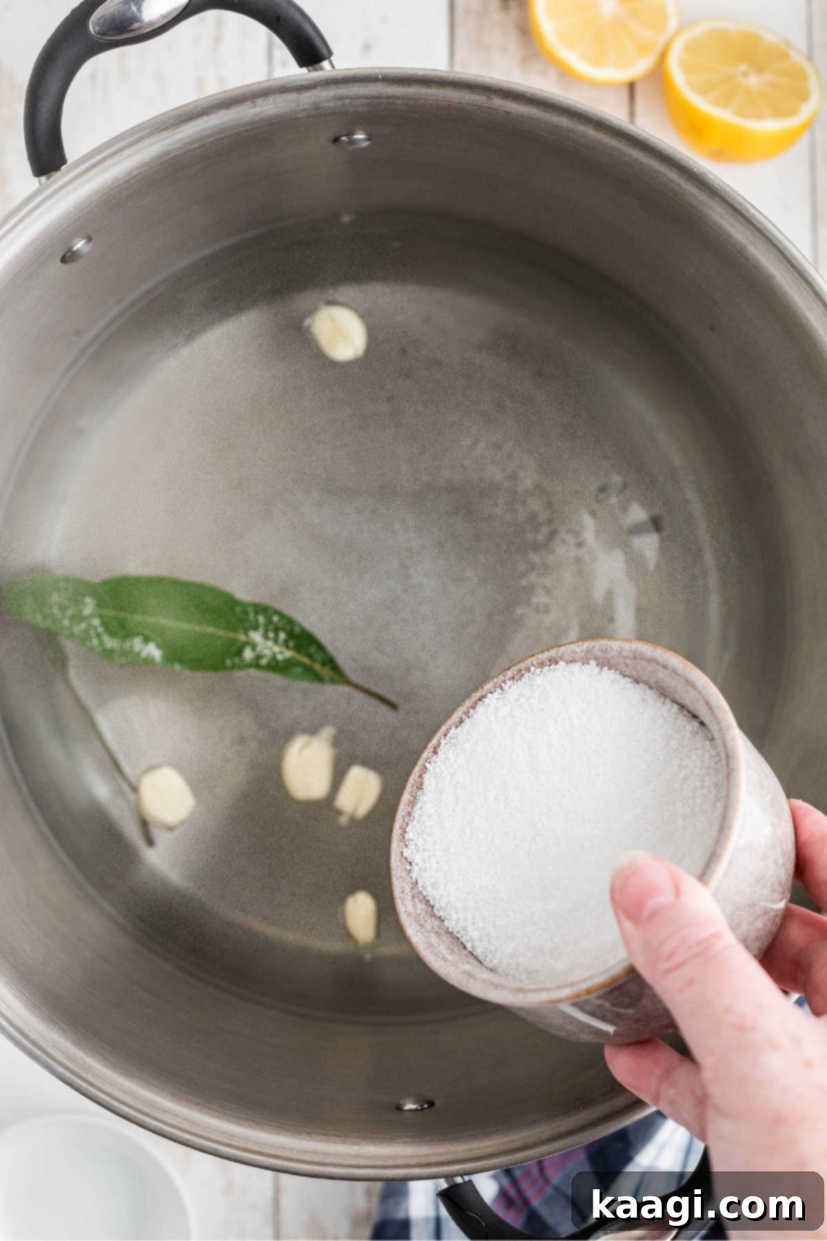 Various seasonings and aromatics added to a large stock pot of water on a stove.