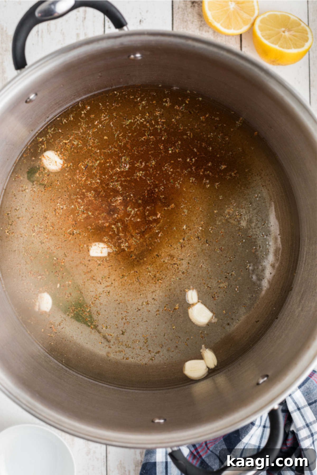 Crushed garlic cloves being added to the stock pot with dissolved salt and sugar.
