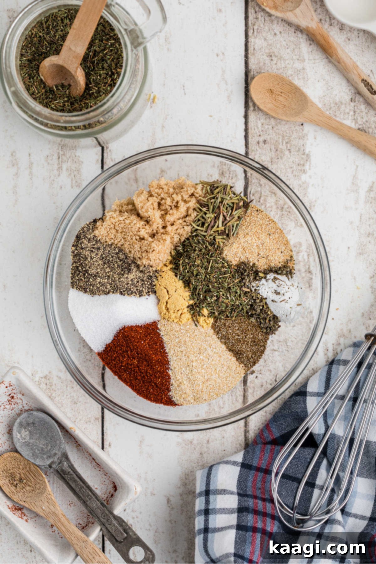 A glass bowl with a lot of different spices about to be mixed together.