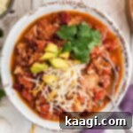 Rich and Hearty Dutch Oven Turkey Chili 12 Overhead shot of a bowl of Dutch Oven turkey chili with cheese and avocado on top, cropped square.