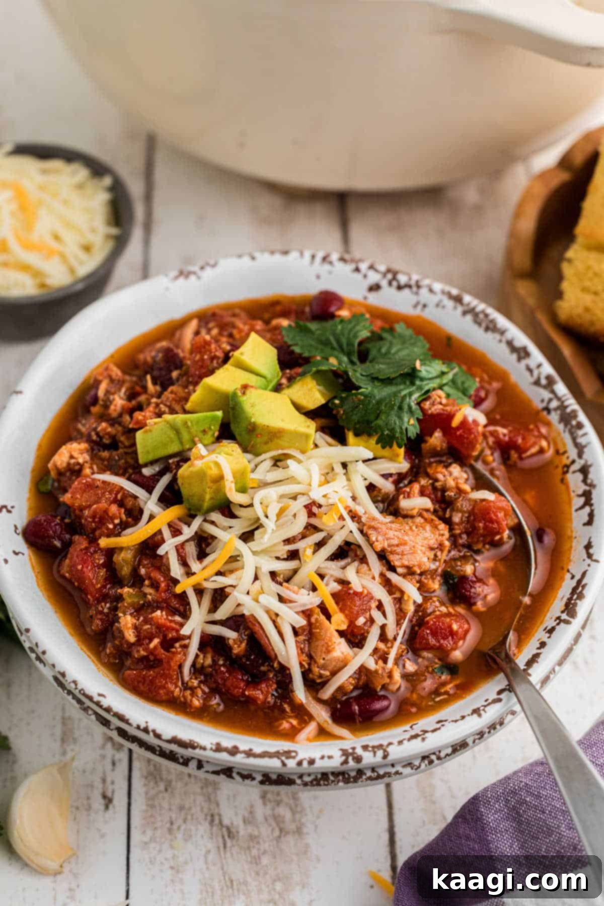 Rich and Hearty Dutch Oven Turkey Chili 8 Side view of a bowl of Dutch Oven Turkey Chili with a spoon digging in.
