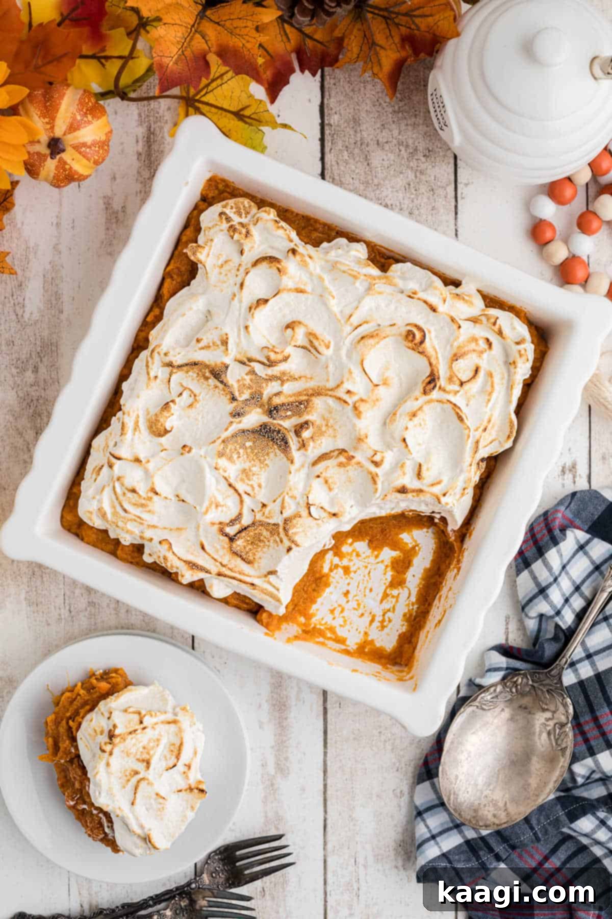 A beautifully presented square dish of golden sweet potato fluff, topped with toasted marshmallow, with a scoop removed, hinting at its irresistible taste.