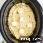 Savory Slow Cooker Mashed Potatoes 13 Overhead image of slow cooker mashed potatoes made with chicken broth, and pats of butter on top.
