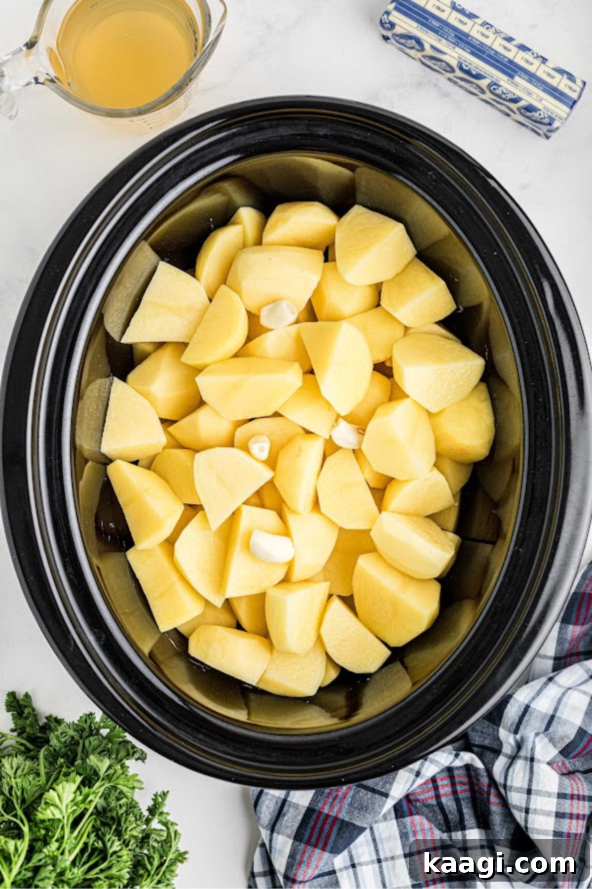 Savory Slow Cooker Mashed Potatoes 5 Chopped potatoes added to a large slow cooker.