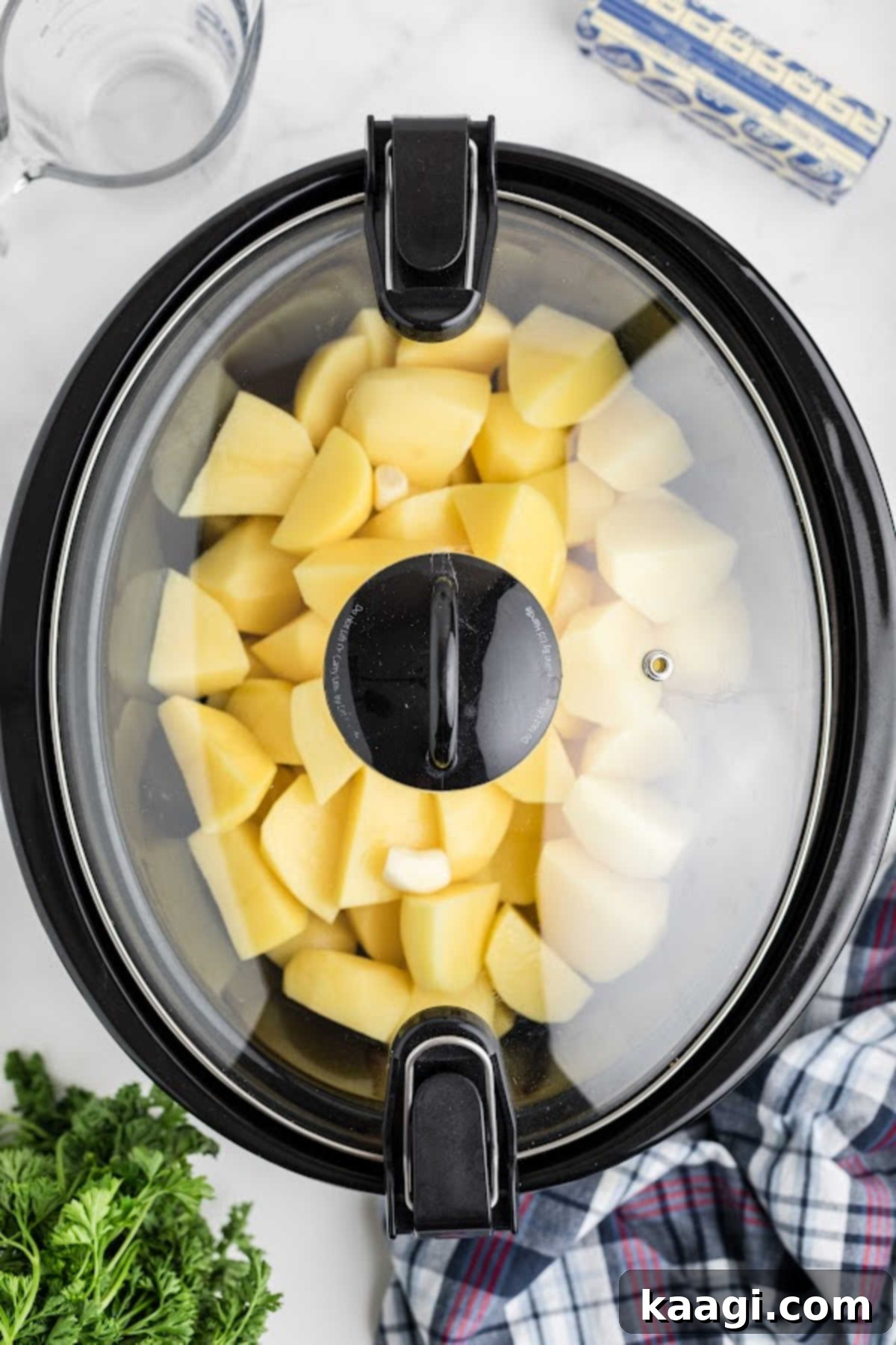 Savory Slow Cooker Mashed Potatoes 7 Potatoes covered and cooking in a slow cooker.