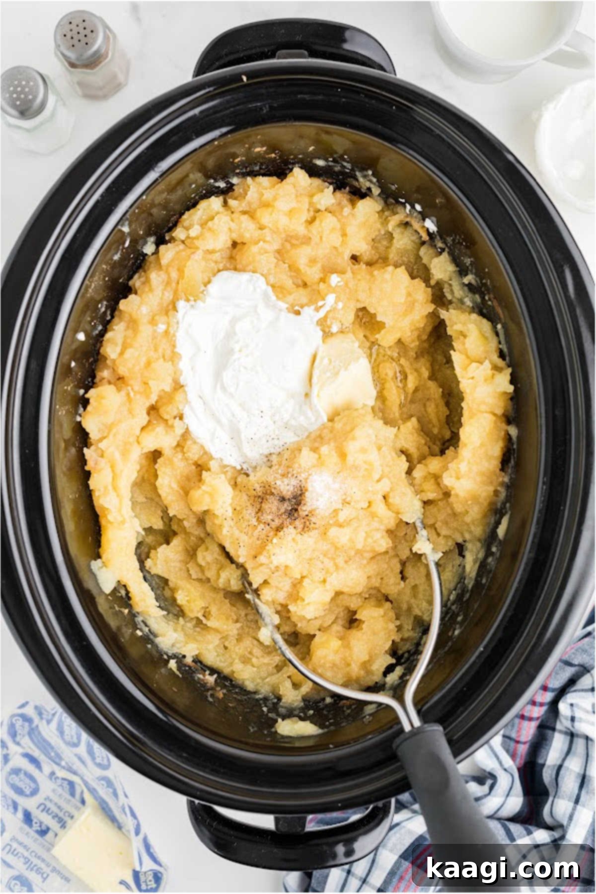 Savory Slow Cooker Mashed Potatoes 9 Sour cream and butter added to a slow cooker full of mashed potatoes.