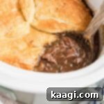 Slow cooker steak pie with a wooden spoon sitting in it.