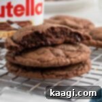 Close up of a Nutella Brownie Cookies recipe with one broke in half, showing its fudgy interior.