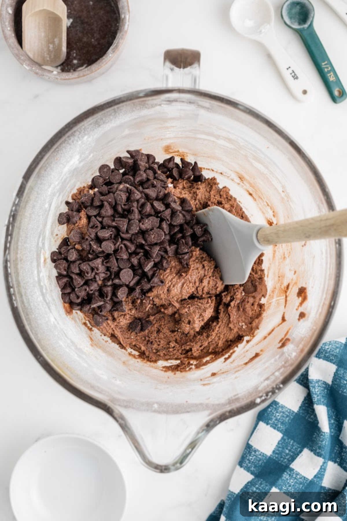 Chocolate chips being gently folded into the Nutella cookie dough with a rubber spatula.