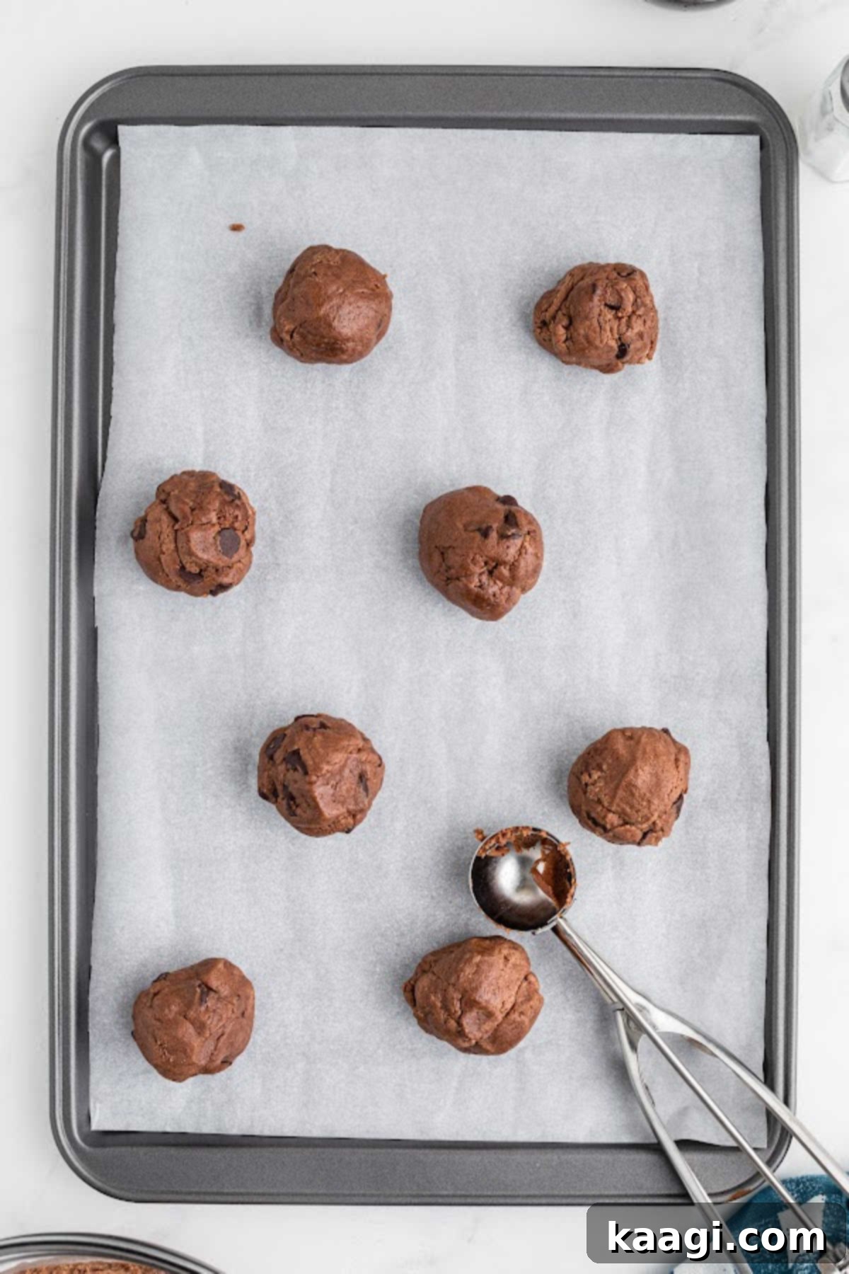 Scoops of Nutella cookie dough placed onto a baking sheet lined with parchment paper.