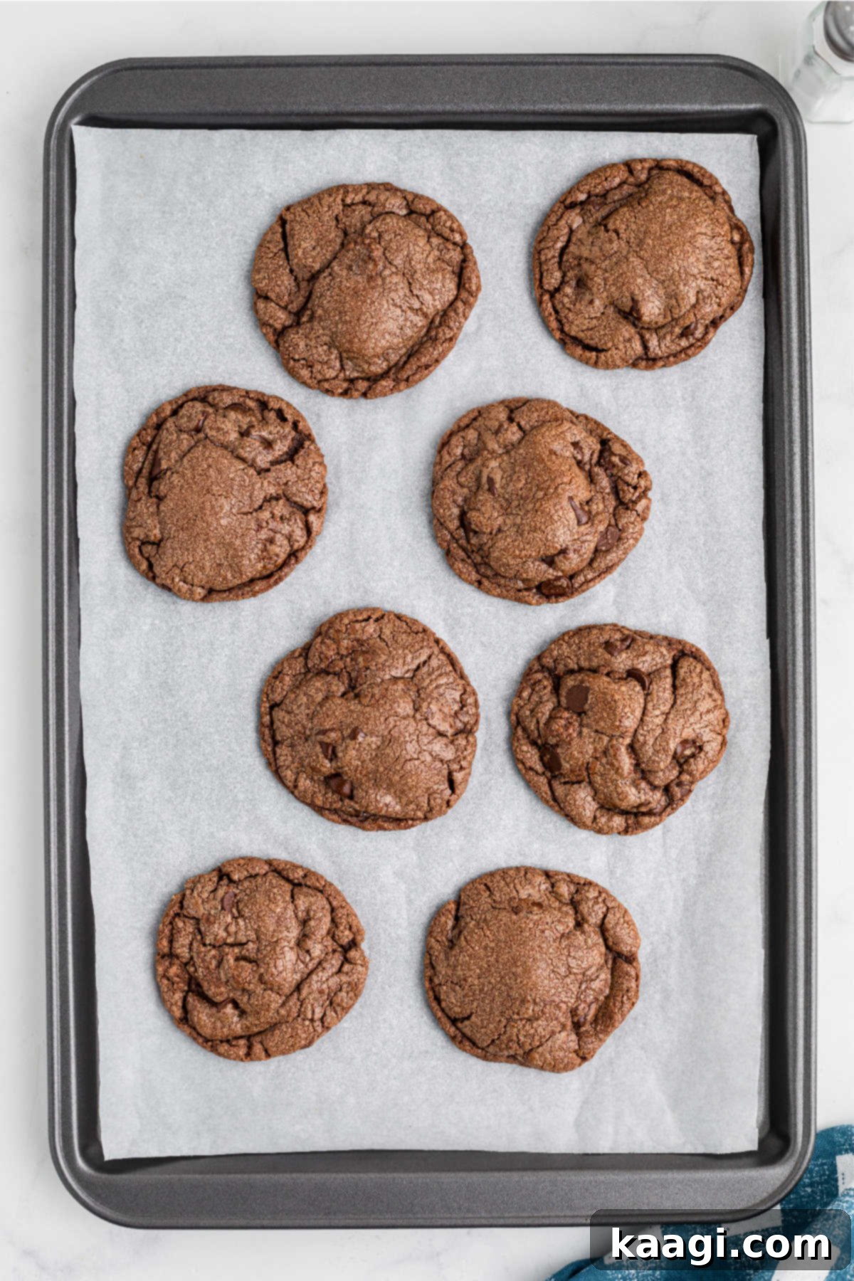 Freshly baked Nutella brownie cookies on a baking sheet, with slightly crinkled tops.