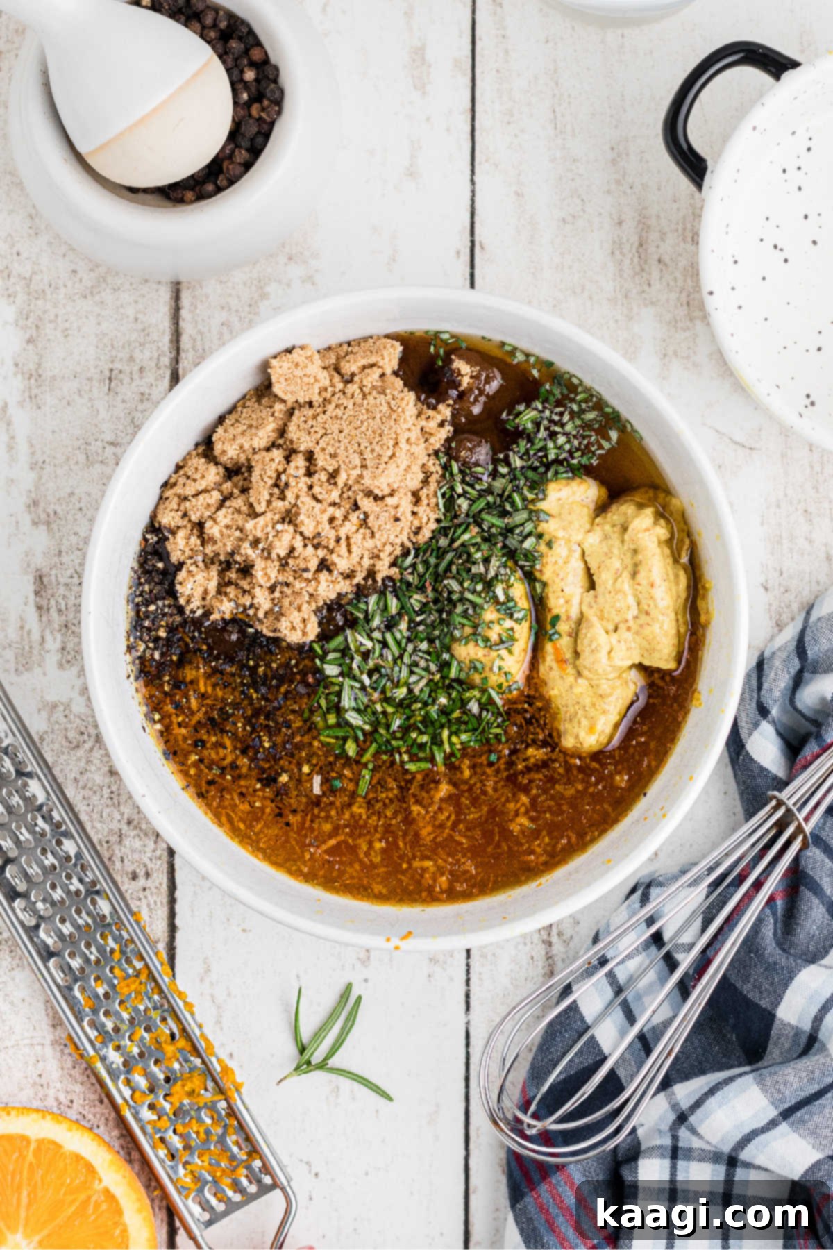 A small mixing bowl full of brown sugar, mustard, honey and herbs being whisked.