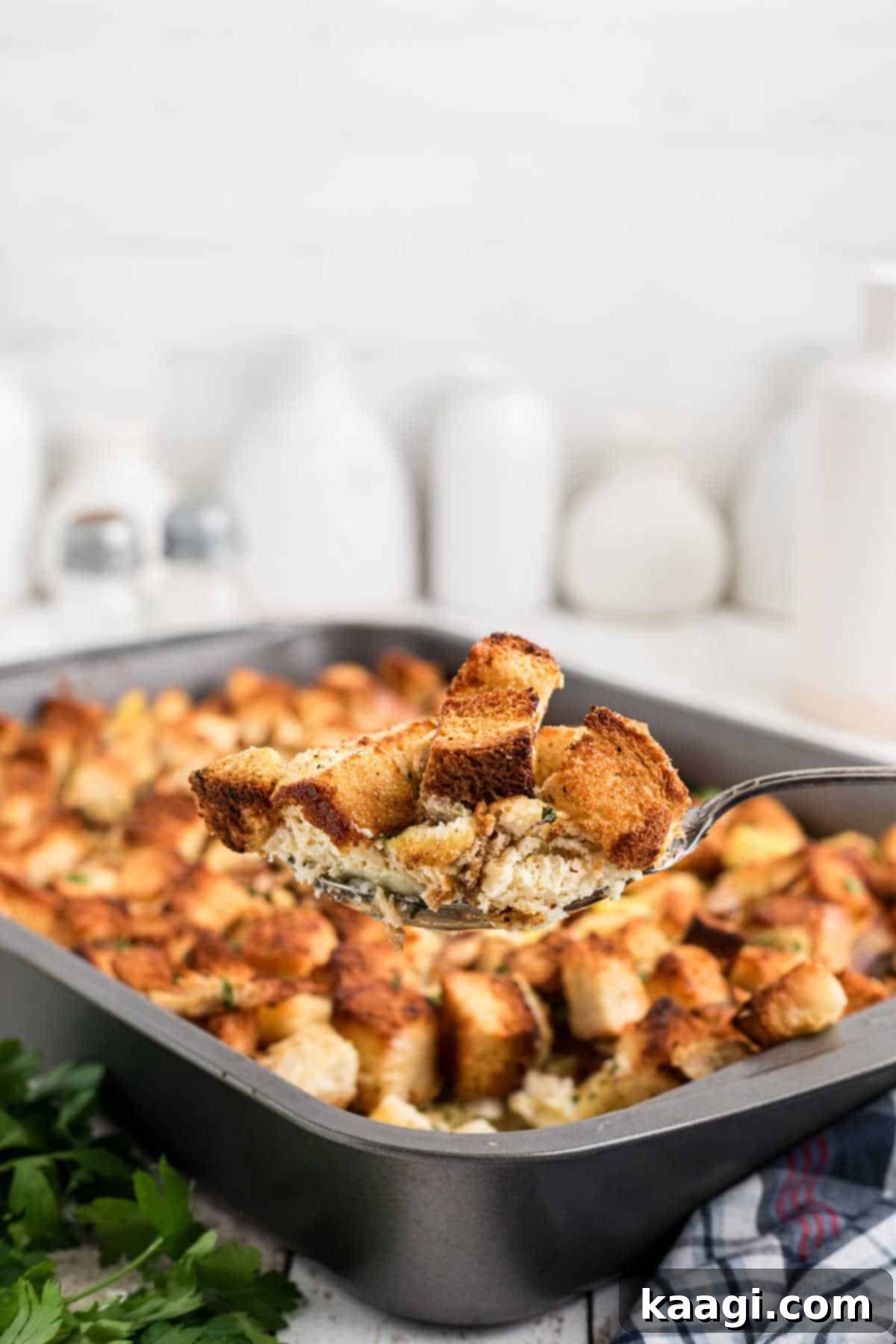 A spoon full of Amish turkey stuffing recipe, being lifted out of the pan.