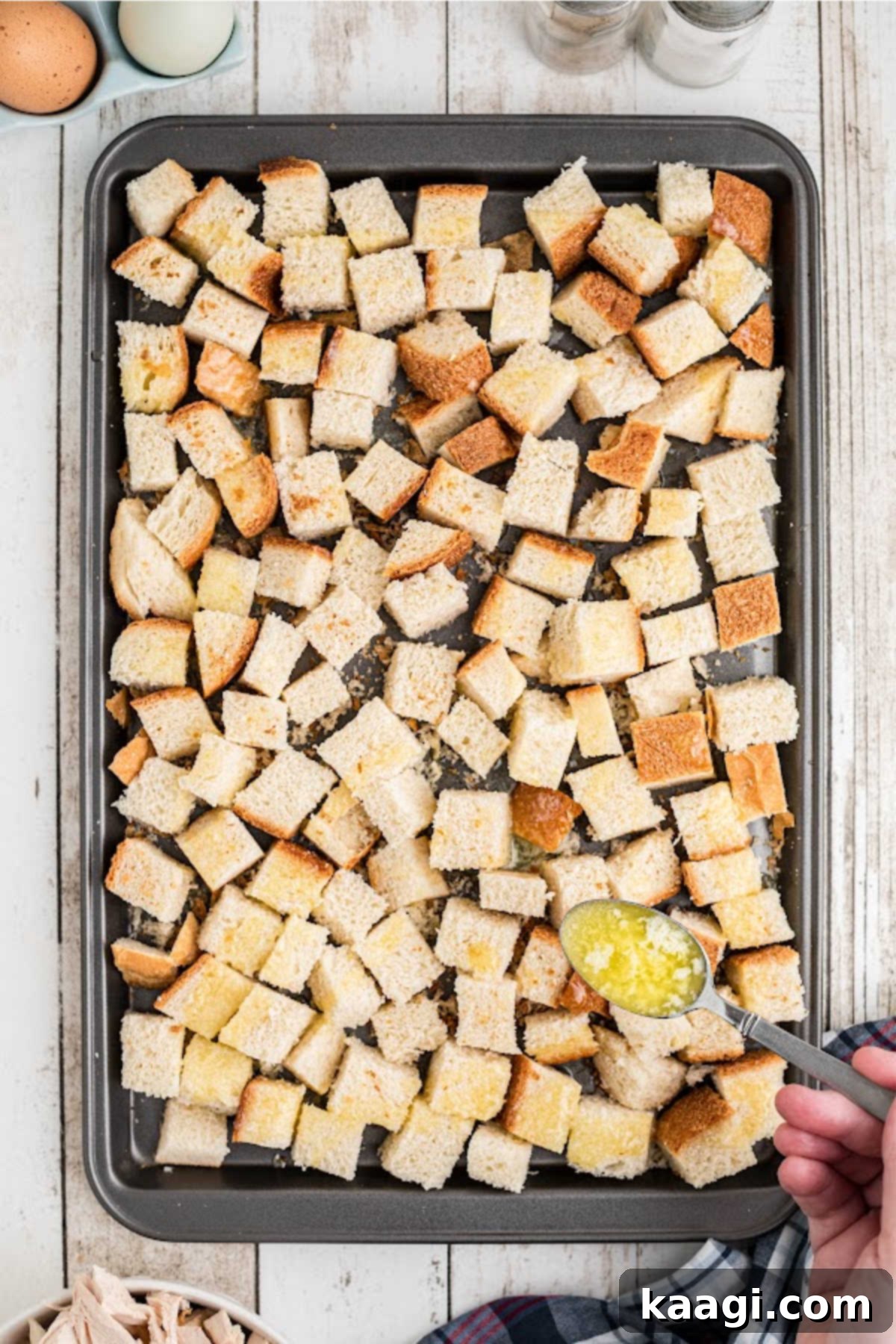 Melted butter being drizzled on bread cubes.