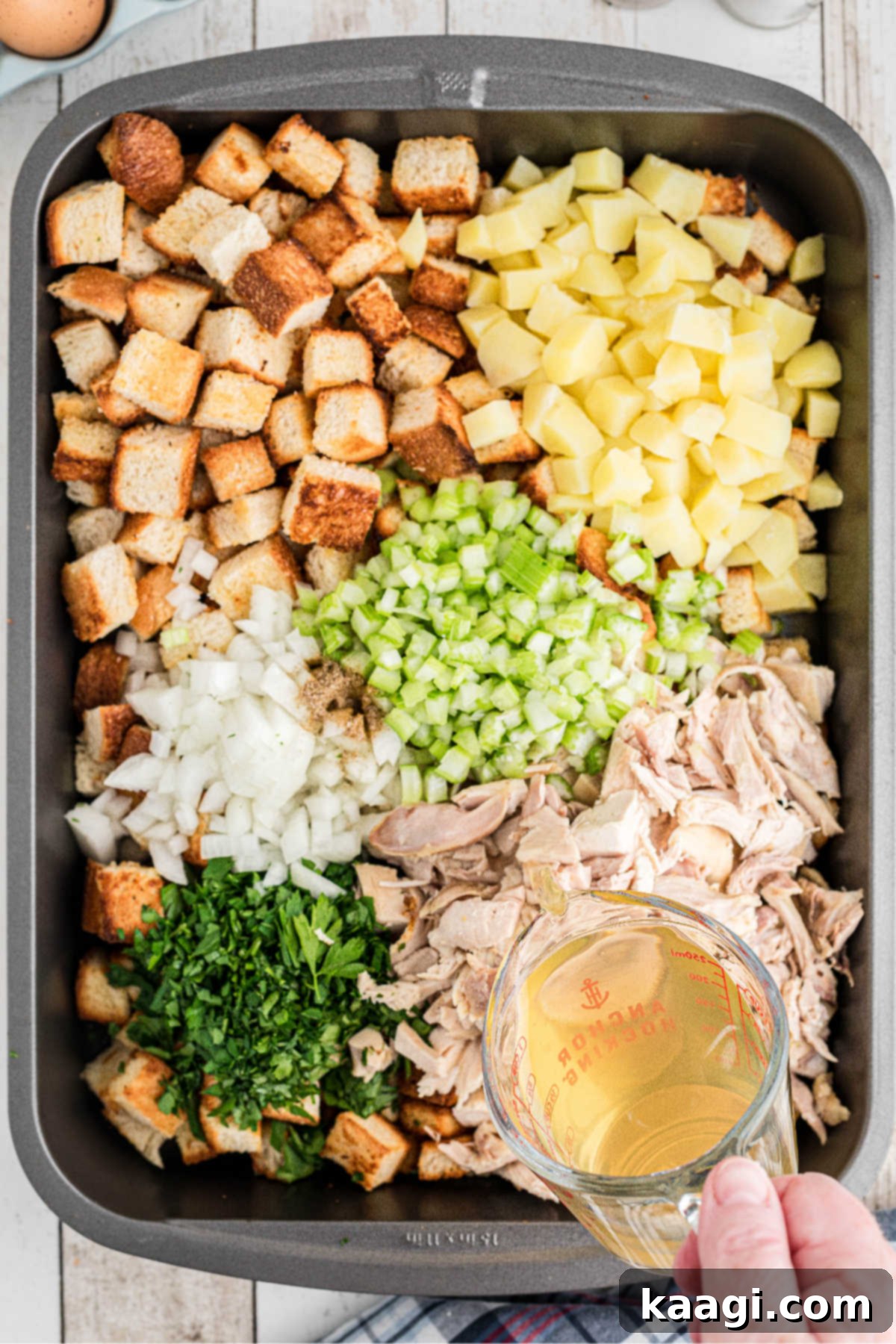 Chicken broth being poured into a large roaster with other ingredients.