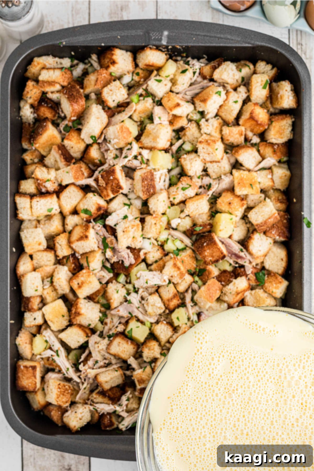 An egg and milk mixture being poured over bread and other ingredients.
