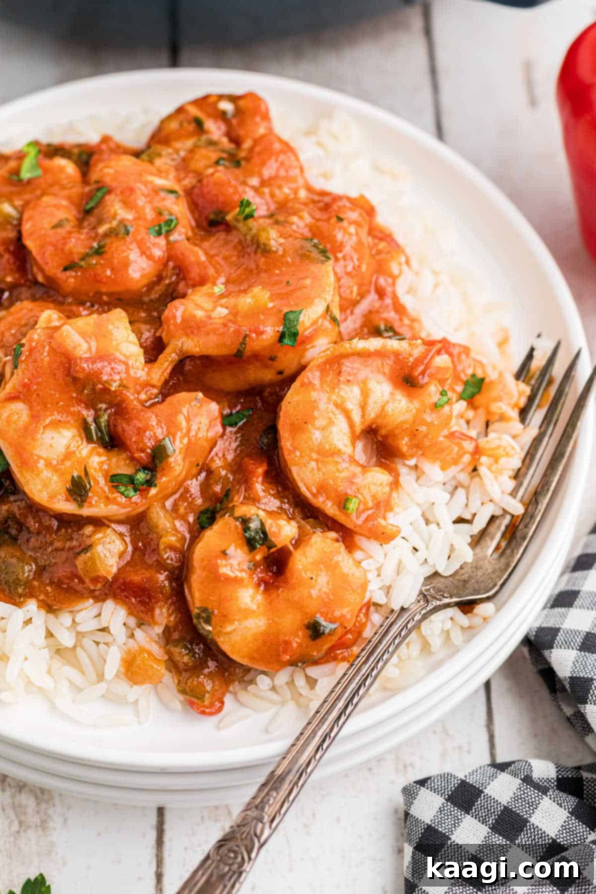 Close up of a plate of New Orleans Shrimp Creole over rice with a fork digging in, highlighting the rich tomato sauce and succulent shrimp.