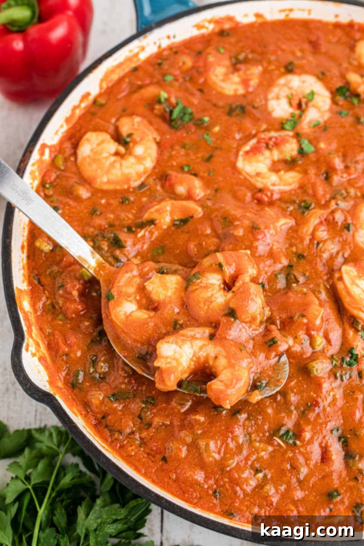 New Orleans Shrimp Creole in a large skillet with a spoon dishing up, showing the texture and richness of the sauce.