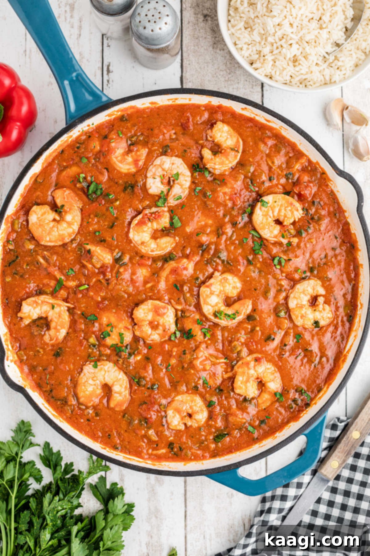 Overhead shot of a skillet full of New Orleans Shrimp Creole, showcasing the vibrant red sauce, shrimp, and green garnishes.