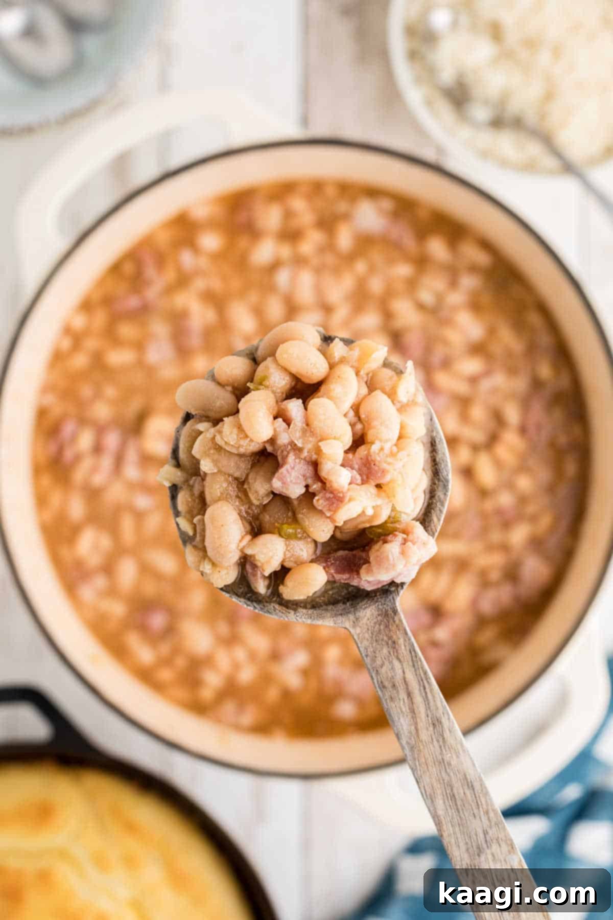 Overhead close up shot of a wooden spoon lifting southern great northern beans out of a pot.