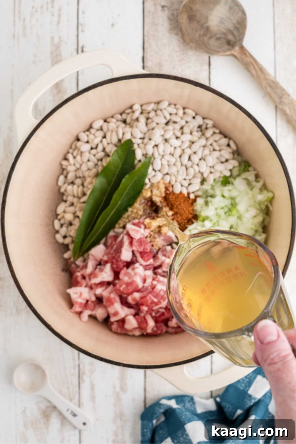 Chicken broth being poured into a large Dutch Oven full of ingredients.