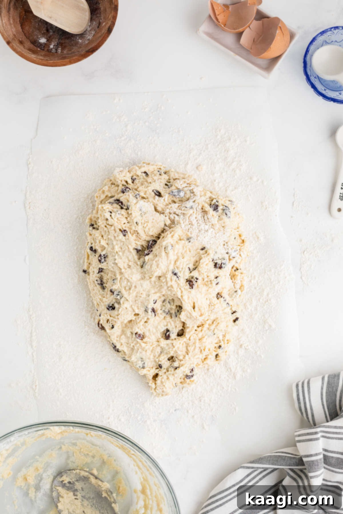 Easy Homemade Irish Soda Bread 9 A bread dough with raisins being gently folded on a floured surface.
