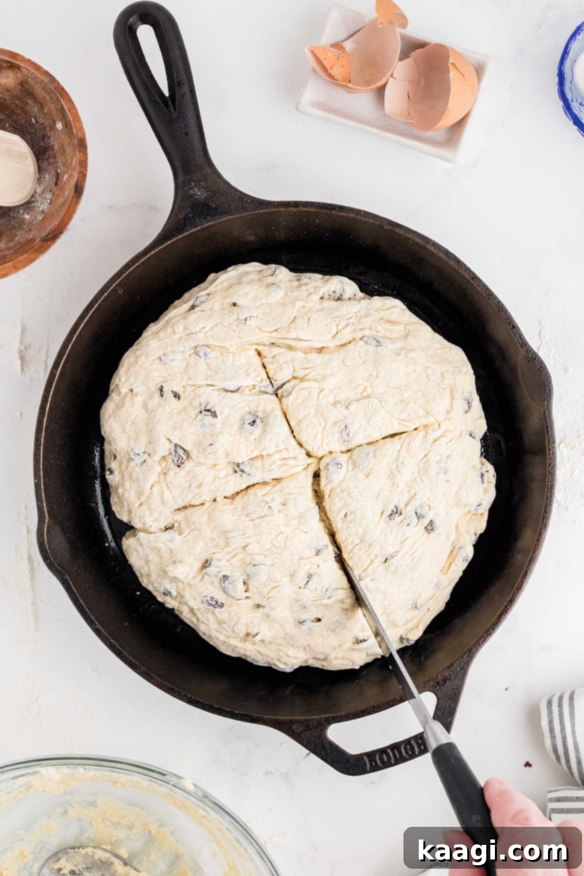 Easy Homemade Irish Soda Bread 10 Soda bread dough placed in a cast iron skillet, being cut with a knife to form a cross.