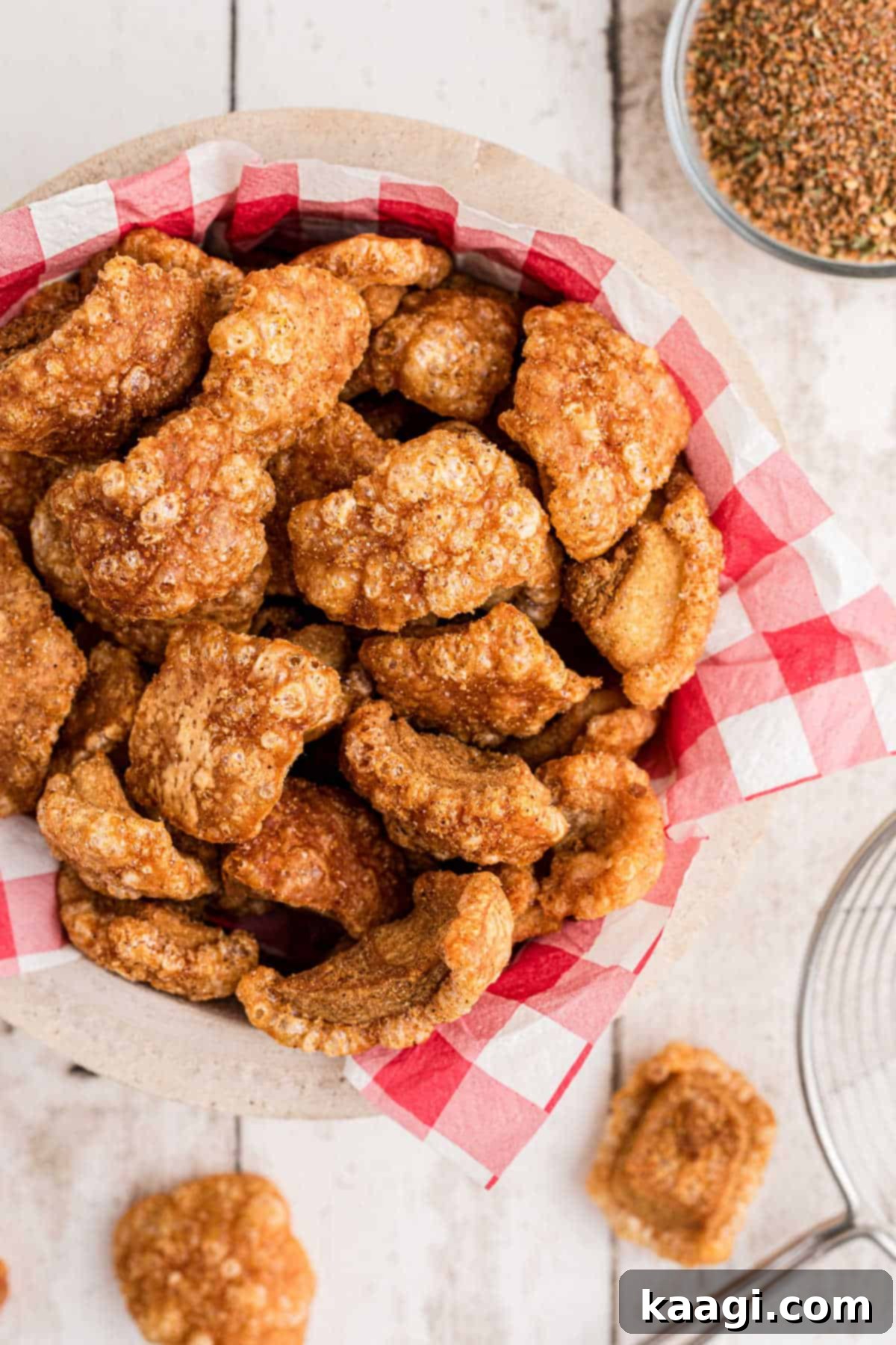 An overhead view of a rustic wooden bowl overflowing with golden, crispy homemade pork cracklins, perfectly seasoned and ready for snacking.