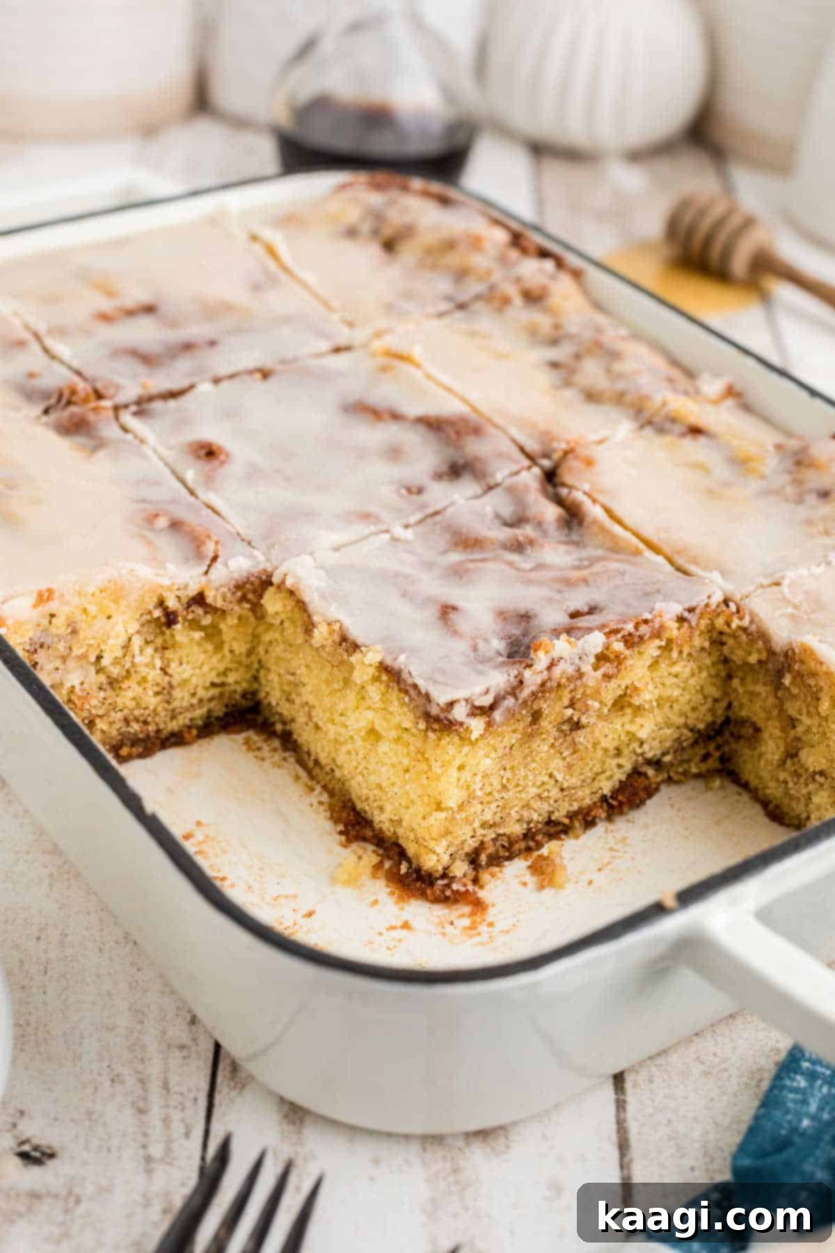 A baking dish filled with a baked honey bun cake, with several slices already removed, showing the soft interior.