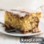 A slice of honey bun cake with icing on top and a fork on the side.