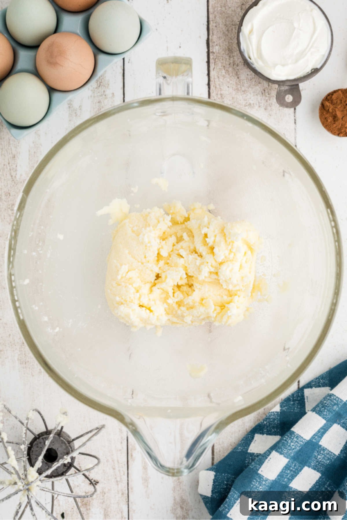 A stand mixer bowl showing softened butter and granulated sugar being creamed together until light and fluffy.