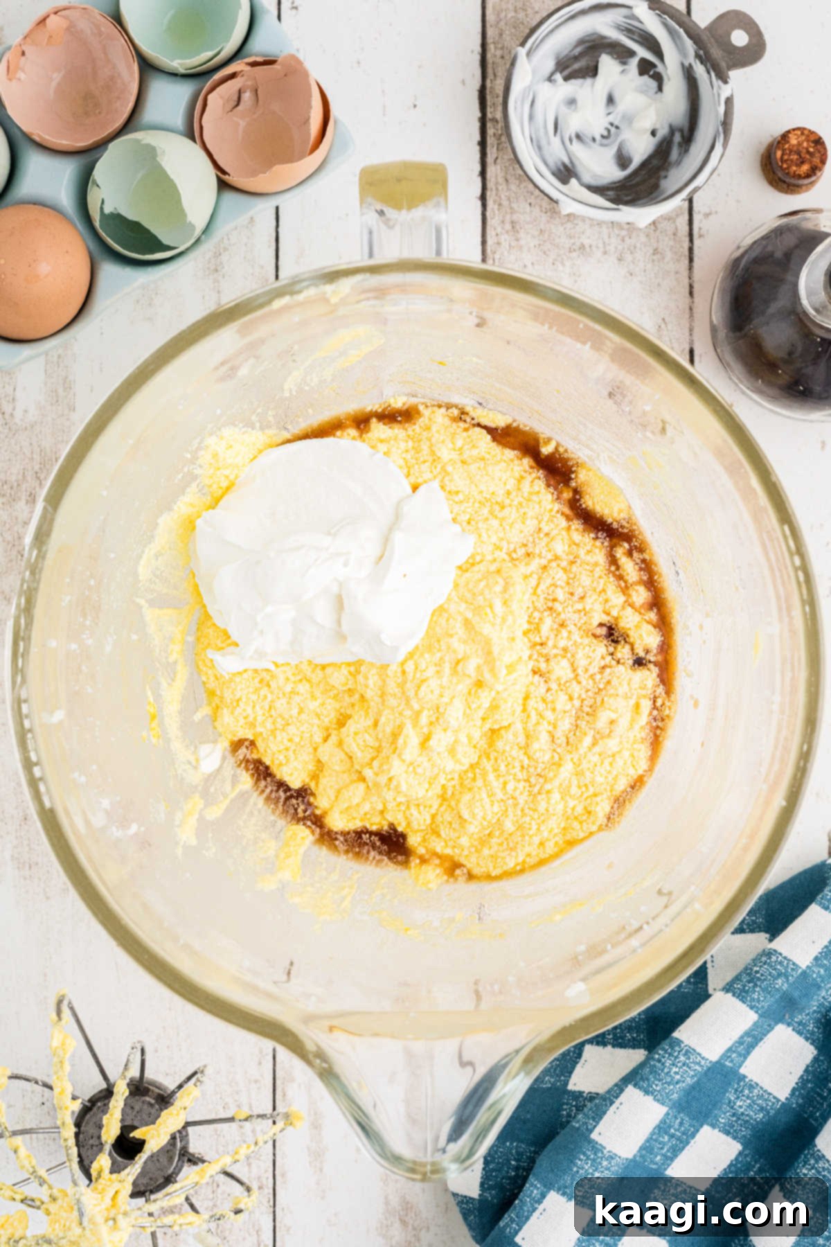 Vanilla extract and sour cream being added to the wet ingredients in a mixing bowl.