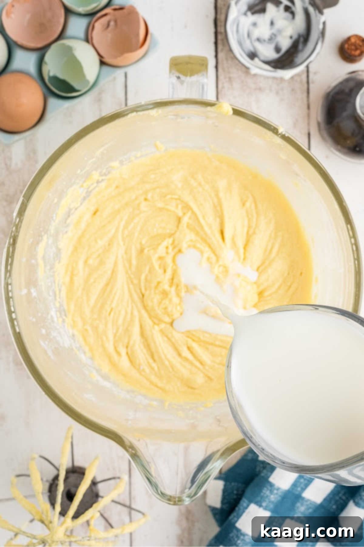 Buttermilk being slowly poured into the cake batter, alternating with the dry ingredients.