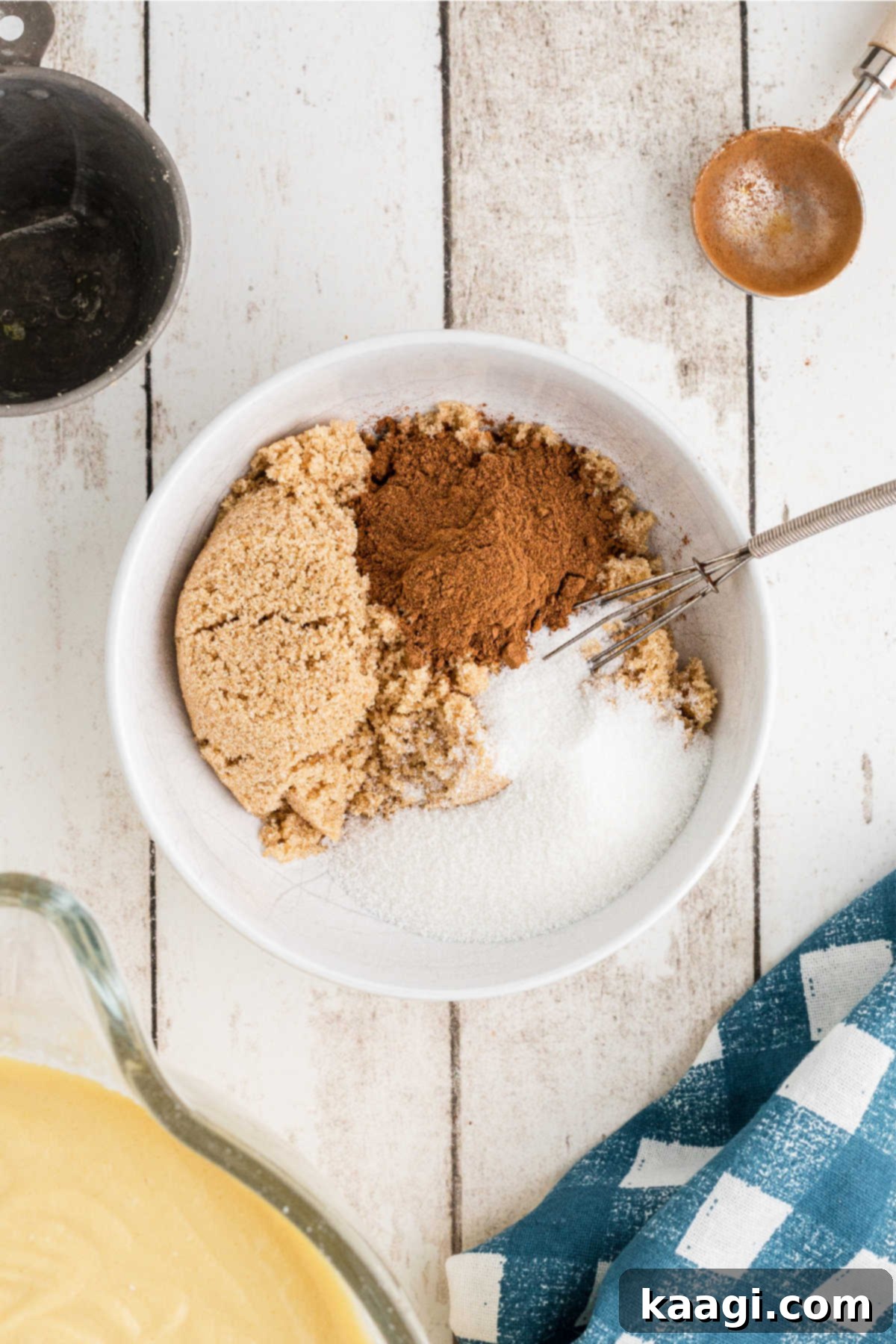 A small bowl containing light brown sugar, granulated sugar, and ground cinnamon, ready to be mixed for the swirl.