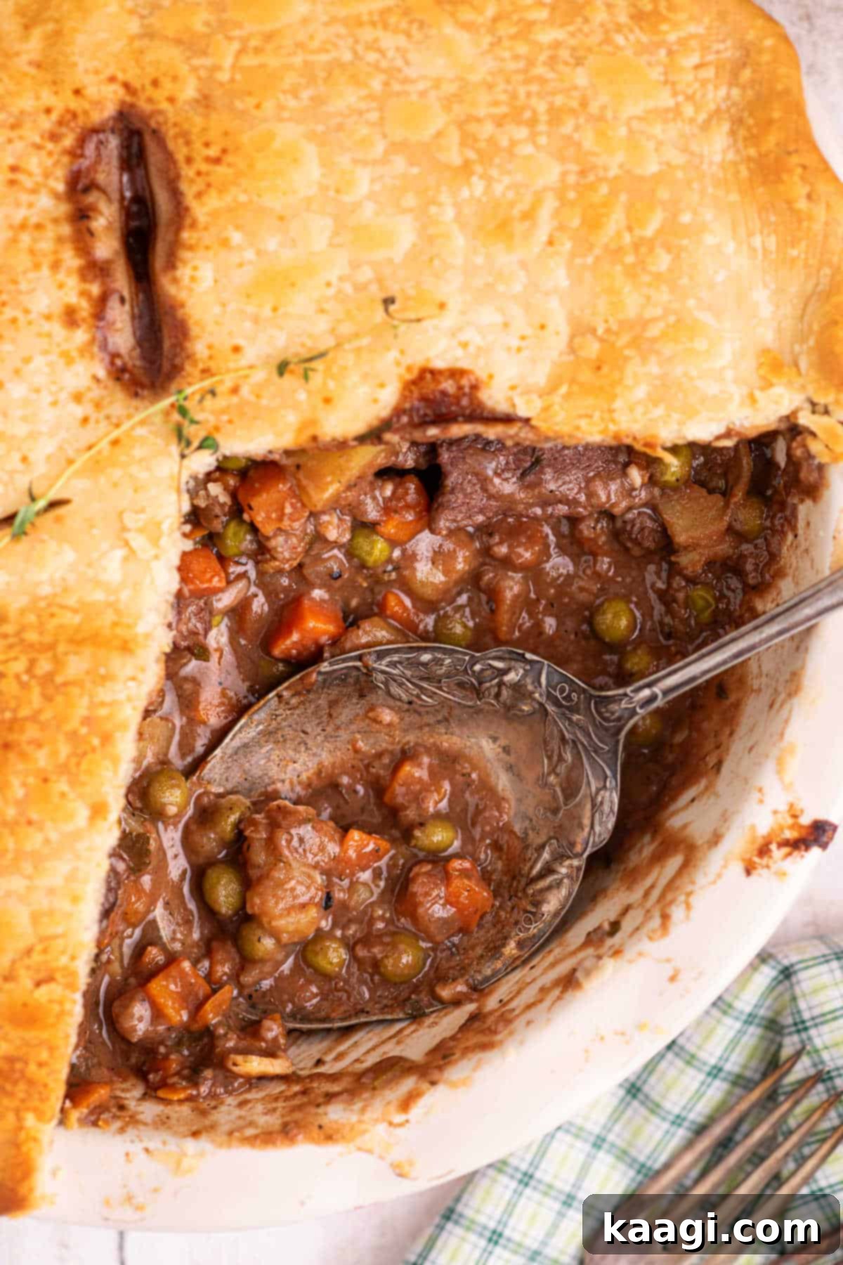 Close up of inside a beef pot pie, with a spoon resting.