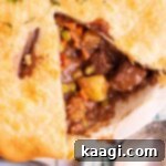A square image of a beef pot pie, close up, with a slice missing.
