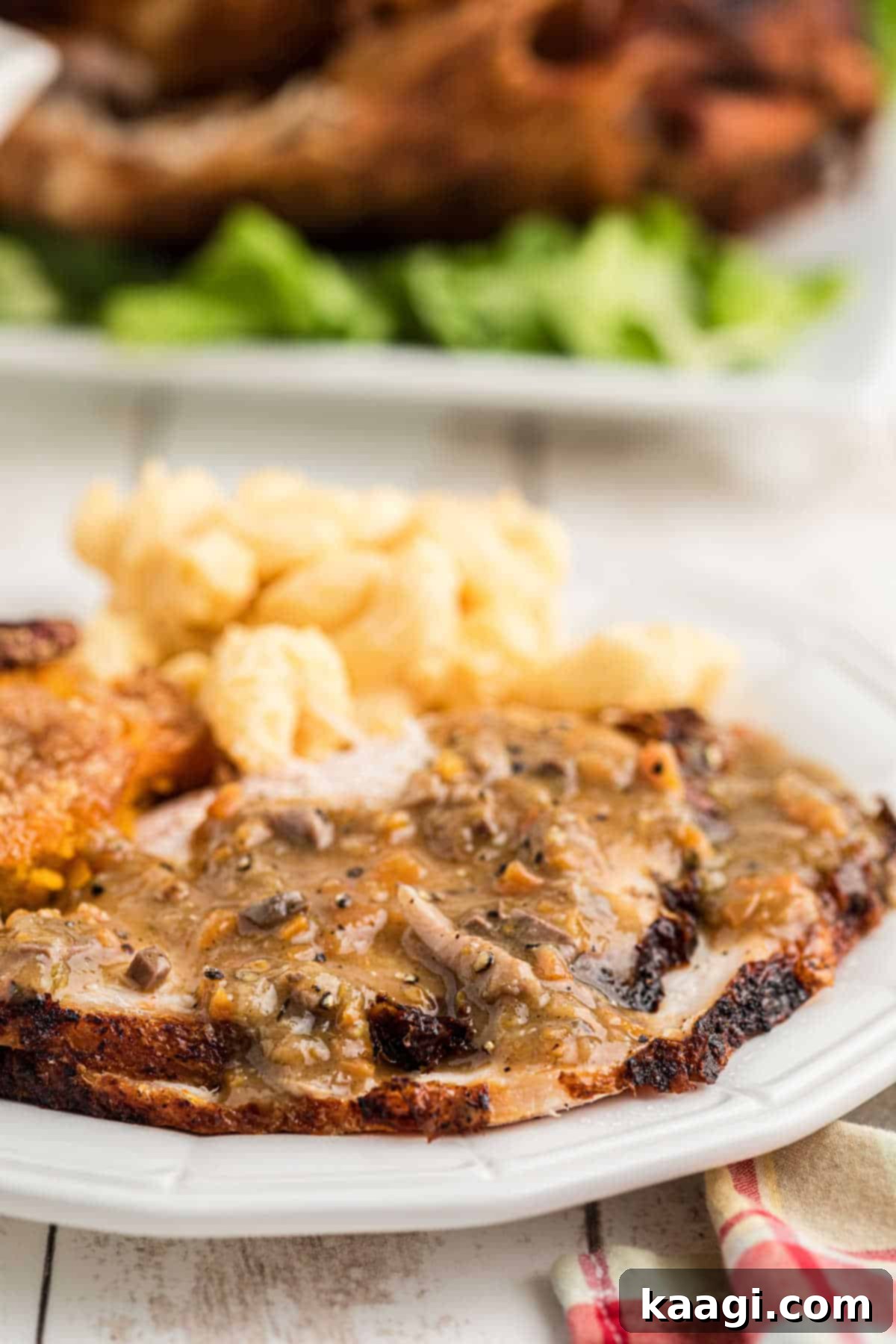 Close up side show of a plate of sliced turkey and sides with a giblet gravy poured on top, highlighting its deliciousness.